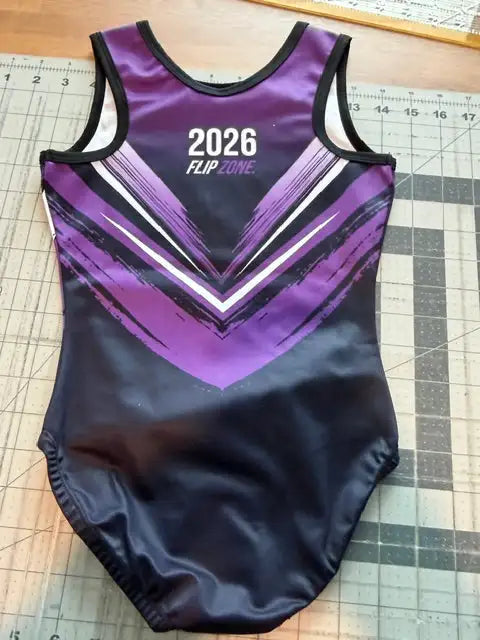 Purple and black sleeveless gymnastics leotard with a shiny, stretchy fabric featuring bold white chevron stripes across the chest.