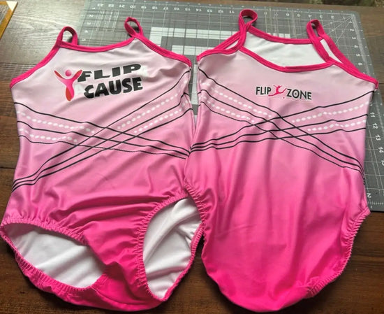 Two pink gymnastics leotards with contrasting black and white graphic designs, featuring the ’flip cause’ and ’flip zone’ logos on their backs.