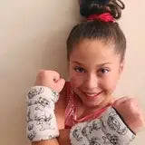 The image shows a young girl wearing white wrist wraps with black patterned designs.